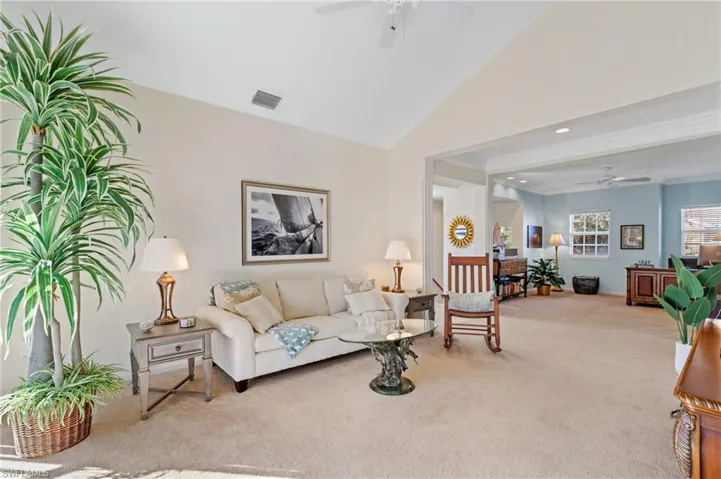 Carpeted living room with ceiling fan and lofted ceiling