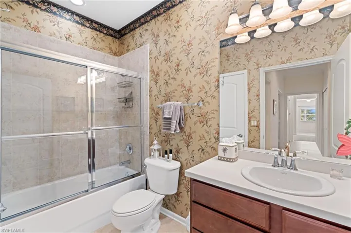 Full bathroom featuring shower / bath combination with glass door, vanity, and toilet