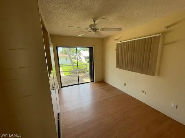 Spare room with a textured ceiling, wood finished floors, and a ceiling fan
