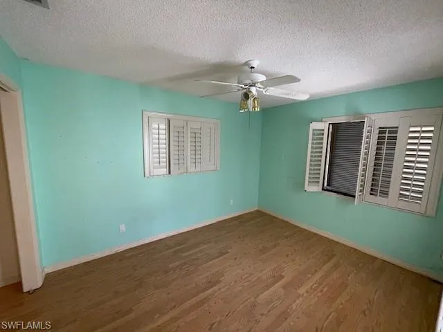 Spare room with a textured ceiling, wood finished floors, and ceiling fan