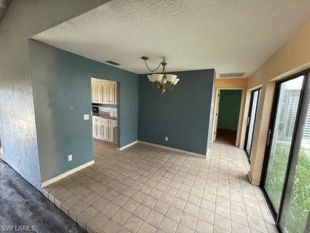 Unfurnished dining area featuring a chandelier, a textured ceiling, and light tile patterned floors