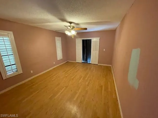 Spare room featuring light wood-type flooring, a textured ceiling, and ceiling fan