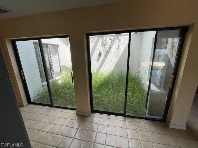 Doorway featuring tile patterned flooring and baseboards