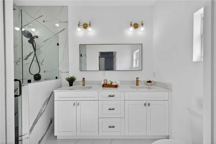 Full bathroom featuring a marble finish shower and double vanity