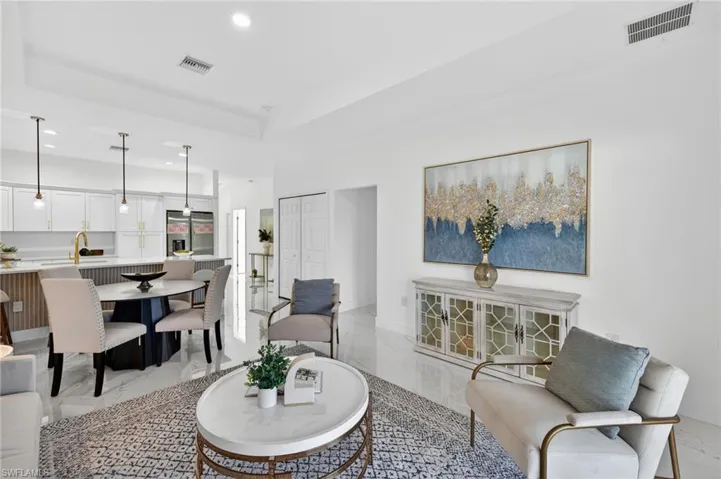 Living room featuring light marble finish flooring, recessed lighting, and a raised ceiling