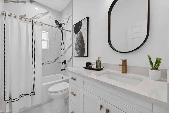 Full bathroom with shower / bath combo with shower curtain, vanity, and light marble finish floors