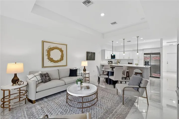 Living area featuring a raised ceiling, recessed lighting, and light marble finish floors