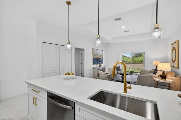 Kitchen featuring white cabinetry, light stone counters, decorative light fixtures, dishwasher, and light marble finish floors