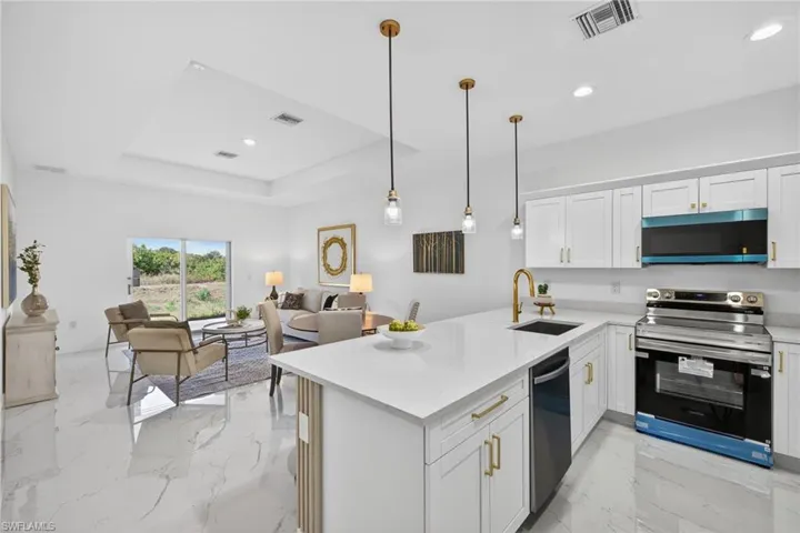 Kitchen featuring light marble finish floors, open floor plan, stainless steel appliances, white cabinets, and recessed lighting