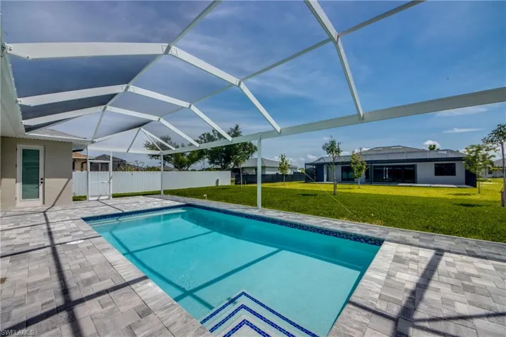 View of swimming pool featuring a patio, a yard, and glass enclosure