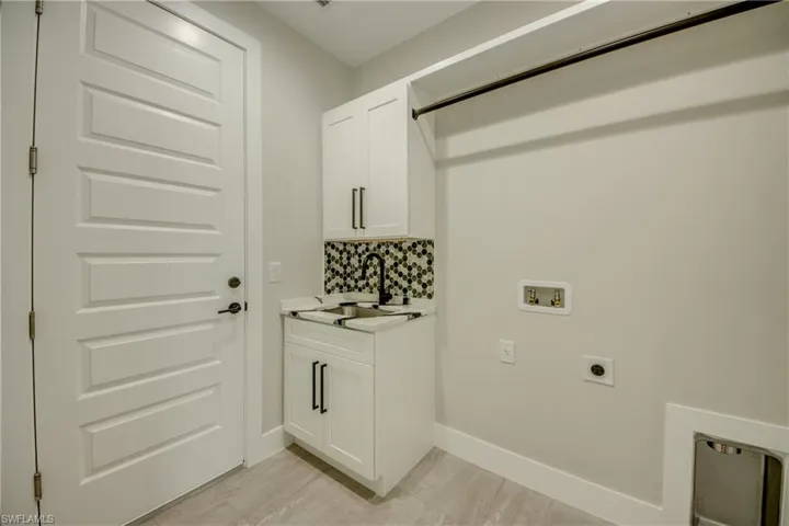 Clothes washing area with hookup for a washing machine, sink, hookup for an electric dryer, and cabinets