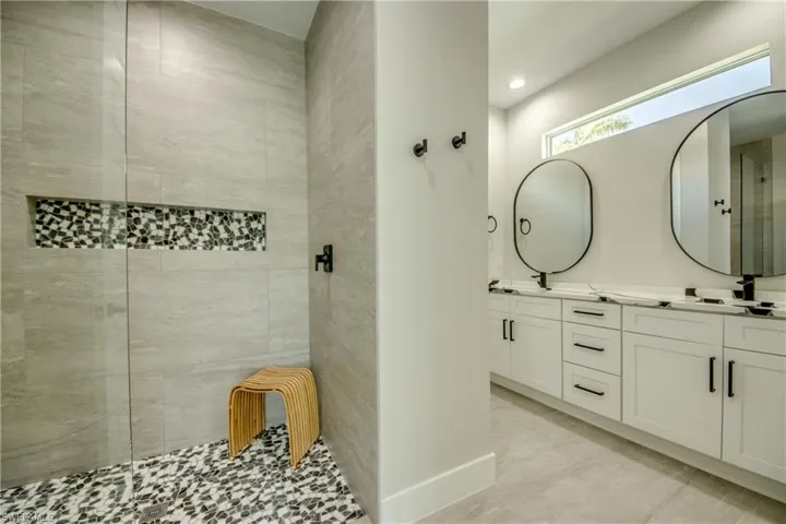 Bathroom featuring dual bowl vanity, a shower with shower door, and tile patterned flooring