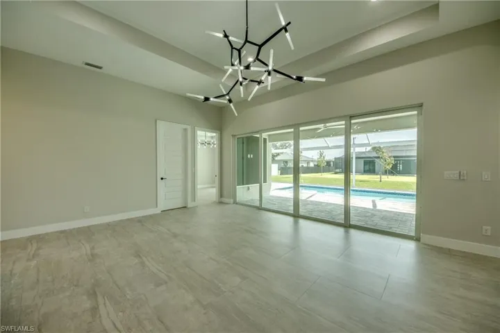 Empty room featuring a tray ceiling, light tile patterned floors, and a chandelier