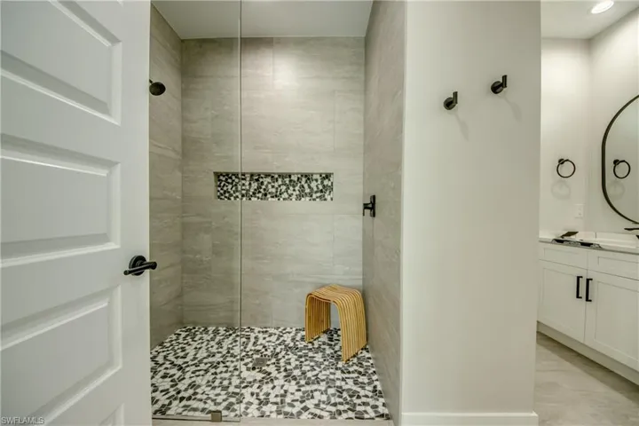 Bathroom featuring a tile shower, vanity, and tile patterned flooring