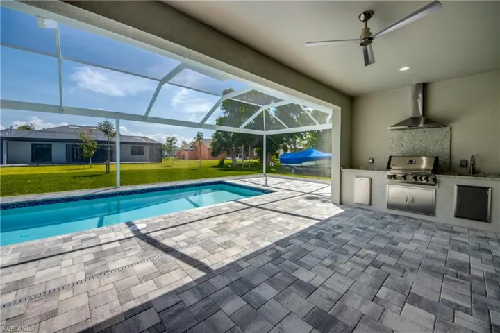 View of swimming pool with a lawn, glass enclosure, area for grilling, a patio, and ceiling fan
