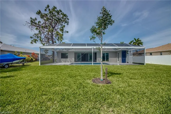 Back of property with a lawn, glass enclosure, and a patio area
