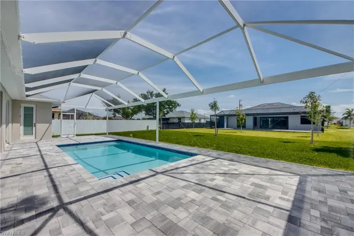 View of swimming pool with glass enclosure, a lawn, and a patio