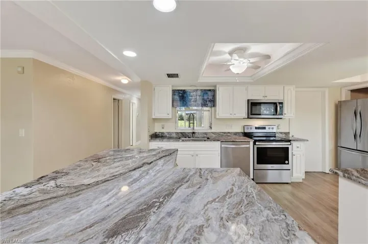 Kitchen featuring stone countertops with waterfall edge, white cabinetry, recessed lighting, ceiling fan, and stainless steel appliances