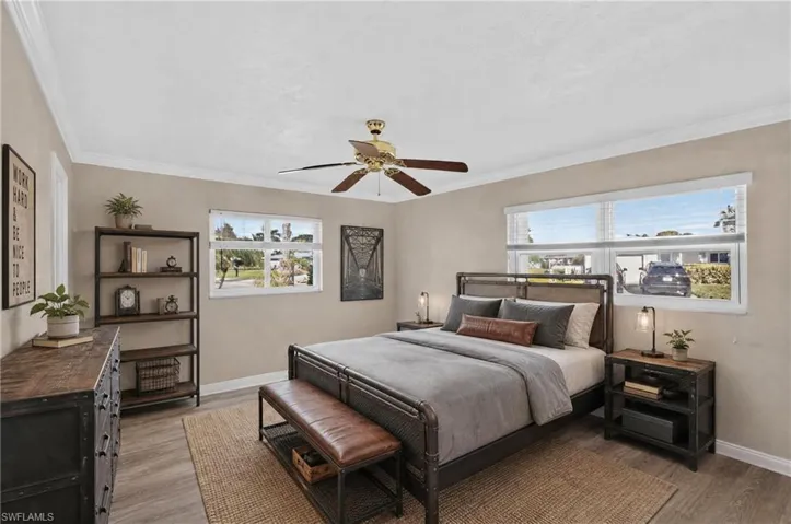 Interior space featuring wood-finish flooring, crown molding, a central ceiling fan, and large windows with horizontal blinds