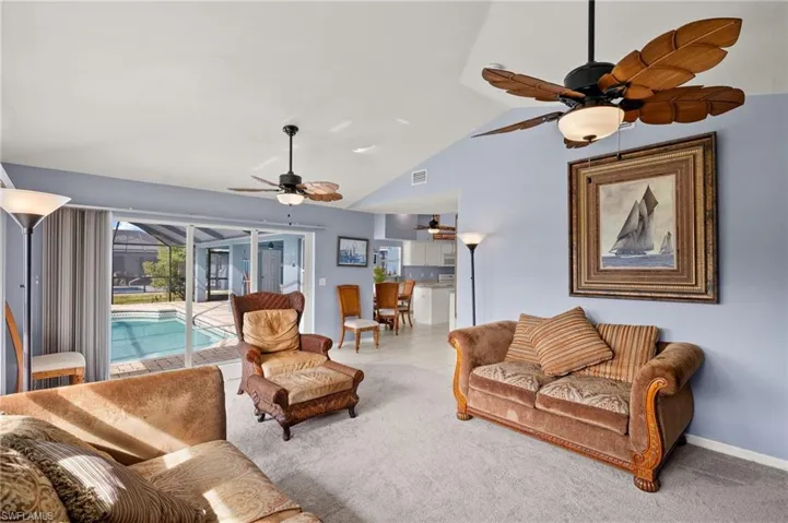 Carpeted living room featuring lofted ceiling and ceiling fan