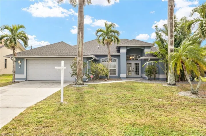 View of front of house featuring a garage, a front yard, and french doors