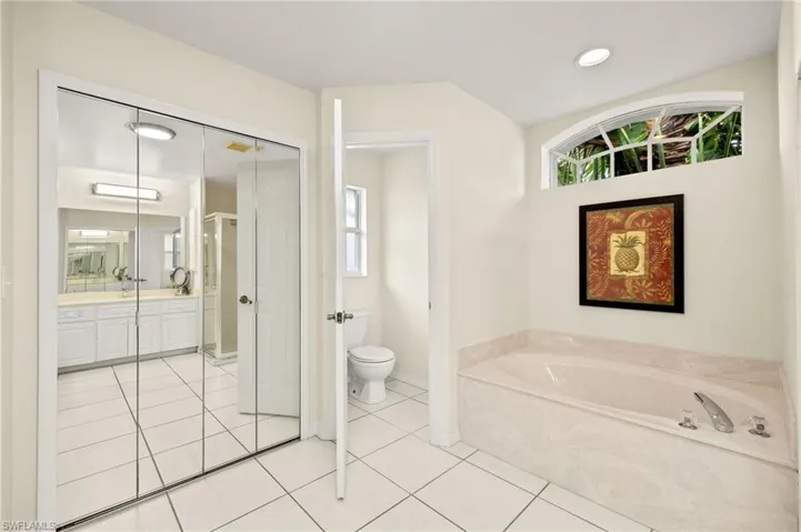 Bathroom with toilet, vanity, tile patterned floors, and a bath