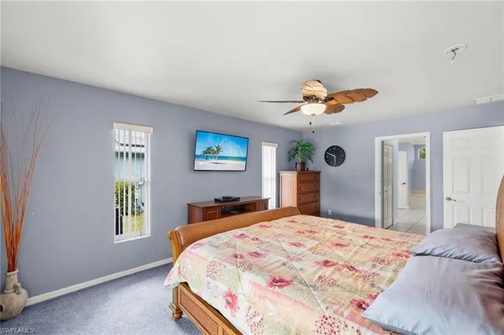Bedroom featuring light carpet, ceiling fan, and ensuite bath