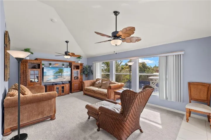 Carpeted living room featuring ceiling fan and vaulted ceiling