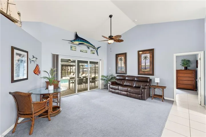 Carpeted living room featuring ceiling fan and high vaulted ceiling