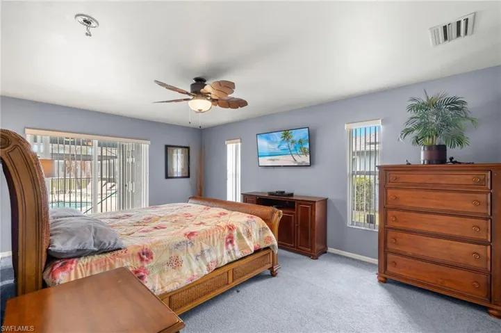Carpeted bedroom featuring ceiling fan, access to exterior, and multiple windows