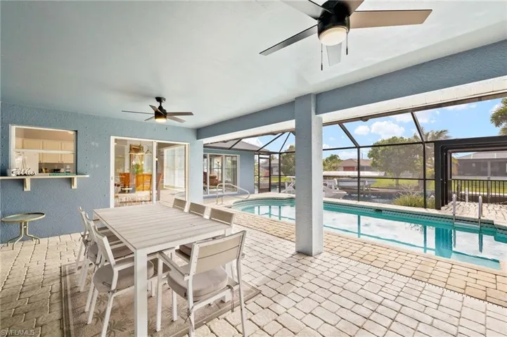 View of pool featuring ceiling fan, glass enclosure, and a patio