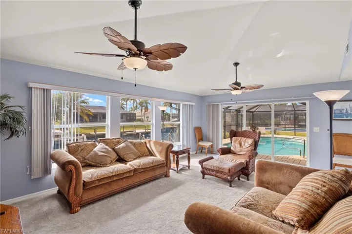 Living room with vaulted ceiling, ceiling fan, a healthy amount of sunlight, and light colored carpet