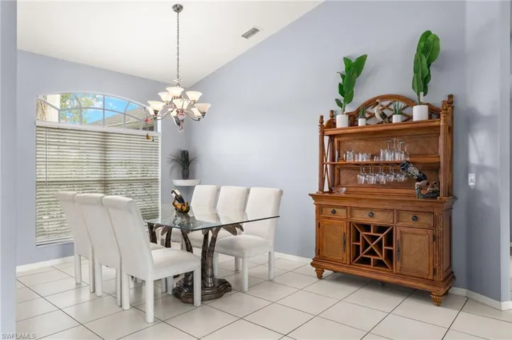 Tiled dining room featuring an inviting chandelier and lofted ceiling