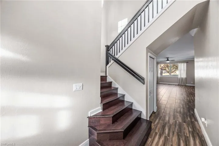 Stairs featuring wood tiled floors, a high ceiling, and a ceiling fan