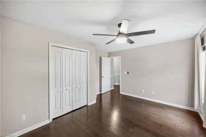 Unfurnished bedroom featuring dark wood finished floors, a closet, and ceiling fan