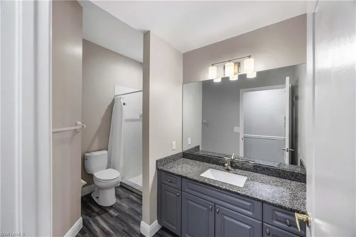 Full bathroom with a shower stall, vanity, and dark wood finished floors