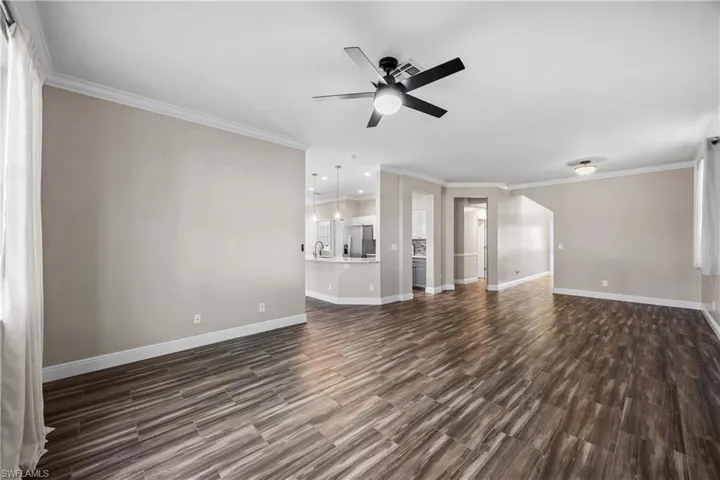 Unfurnished living room with ceiling fan, ornamental molding, and wood finish floors