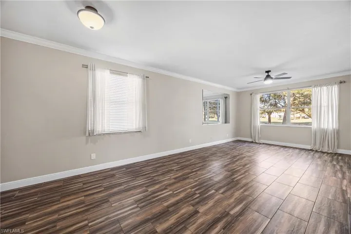 Empty room featuring crown molding, a ceiling fan, and wood finish floors