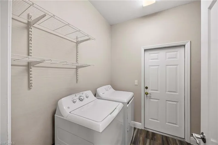 Laundry room with washer and clothes dryer and dark wood-style flooring