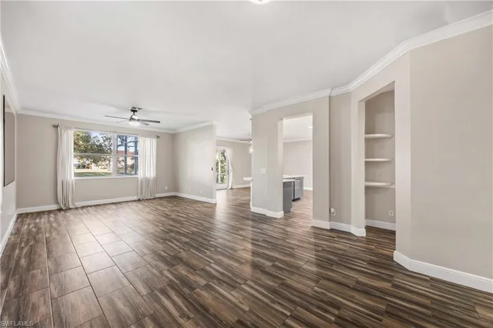 Unfurnished living room with wood tiled floors, a ceiling fan, ornamental molding, and built in features