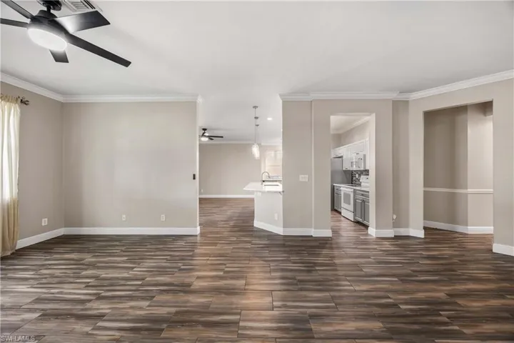 Unfurnished living room featuring a ceiling fan, wood tiled floors, and ornamental molding