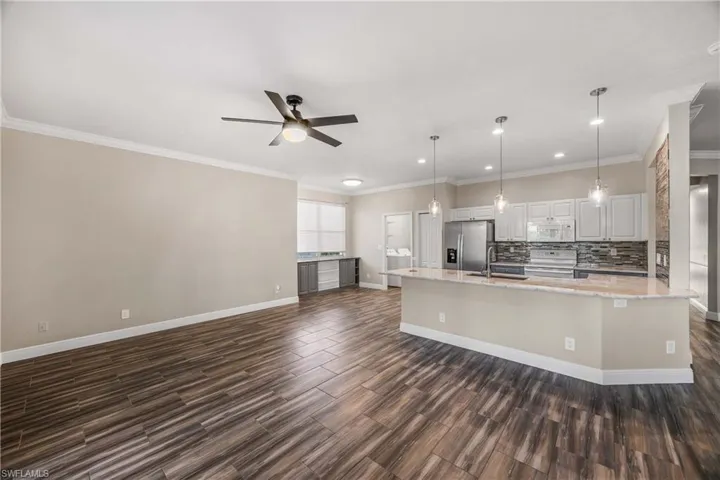 Kitchen with open floor plan, white cabinetry, hanging light fixtures, a ceiling fan, and stainless steel appliances