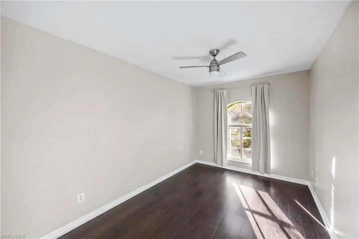 Unfurnished room featuring dark wood-style flooring and ceiling fan