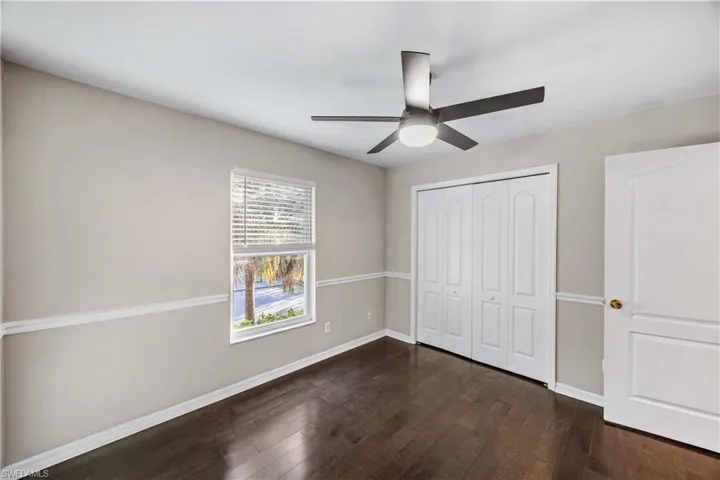 Unfurnished bedroom with dark wood-style flooring, a closet, and ceiling fan