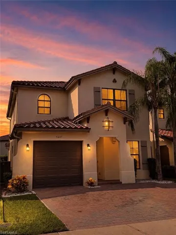 Stucco exterior with a tile roof, arched entryway, and a paved driveway