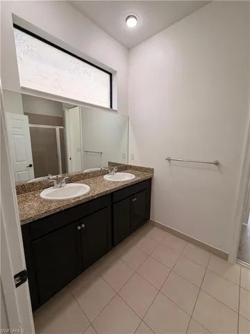 Dual vanity with granite countertops, integrated sinks, dark wood-finish cabinetry, and an expansive wall mirror