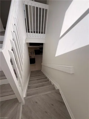 Staircase featuring wood-finish treads, white painted risers, white balusters, and a white handrail
