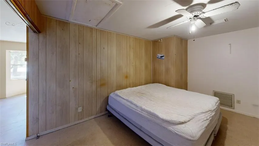 Bedroom featuring ceiling fan and wood walls