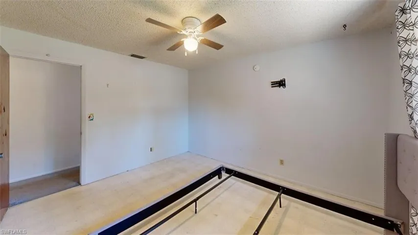 Empty room with light floors, a textured ceiling, and ceiling fan