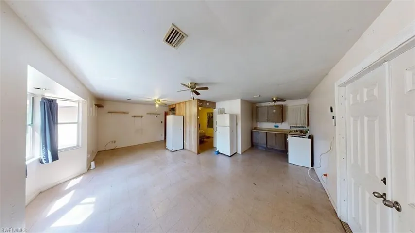 Unfurnished living room featuring light flooring and a ceiling fan